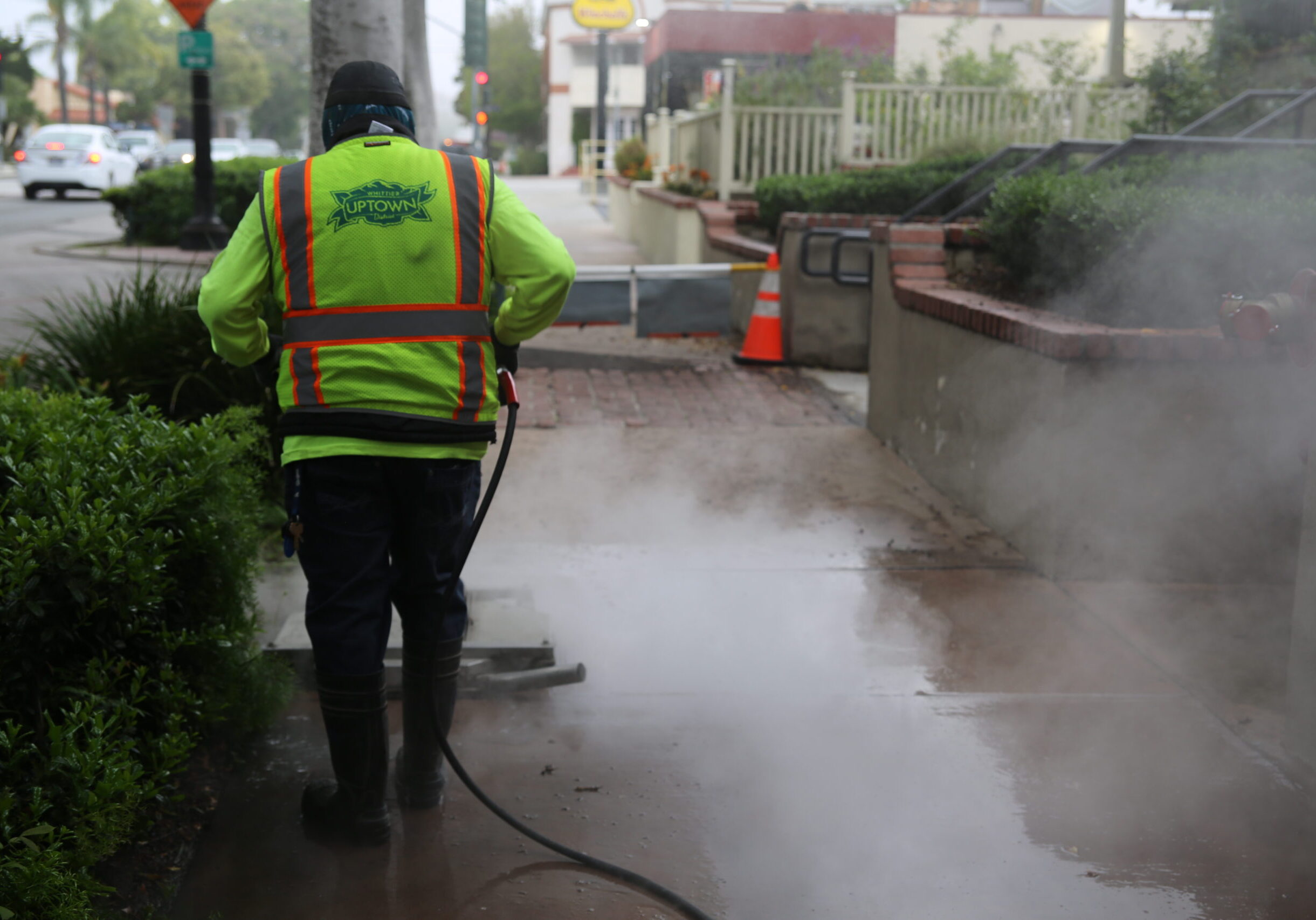 Maintenance vendor using a power washer to clean the sidewalk in Uptown Whittier